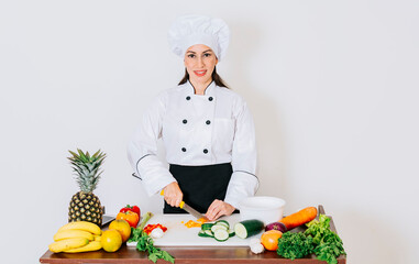 Chef cutting vegetables with knife, smiling cook woman, woman in chef uniform cutting fruits and vegetables