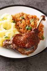 Romanian Rata pe varza duck leg serving with mashed potatoes and stewed cabbage close-up in a plate on the table. Vertical