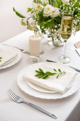 Wedding teble decoration with white flowers, glasses and white napkins. Elegantly decorated table at a wedding reception. Festive table setting. The wedding decor.