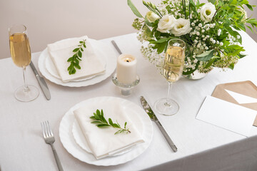 Wedding teble decoration with white flowers, glasses and white napkins. Elegantly decorated table at a wedding reception. Festive table setting. The wedding decor.