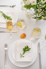 Wedding teble decoration with white flowers, glasses and white napkins. Elegantly decorated table at a wedding reception. Festive table setting. The wedding decor.