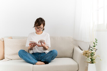 家のソファで読書するおしゃれな日本人女性（本・漫画・小説）
 - obrazy, fototapety, plakaty
