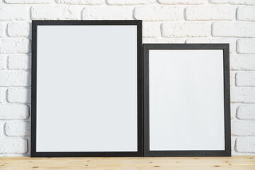 Photo frames on floor over white brick wall