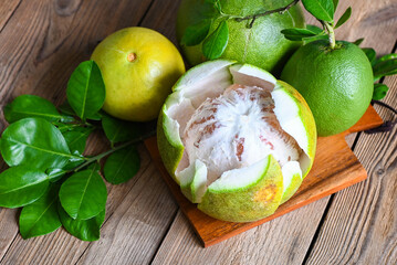 Fresh green pomelo peeled and leaf frome pomelo tree , pomelo fruit on wooden plate  background,...