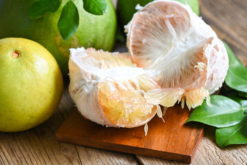 Fresh green pomelo peeled and leaf frome pomelo tree , pomelo fruit on wooden plate  background, pummelo , grapefruit in summer tropical fruit  in thailand