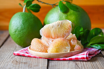 pomelo fruit on wooden plate  background, fresh green pomelo peeled and leaf frome pomelo tree ,...