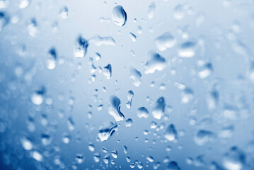 water drop glass background , nature blue with water drop after rain , raindrops on glass window in the rainy season