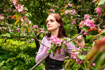 Portrait teenage girl walking in spring park in blooming apple trees