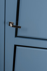Modern chrome door handle on blue door