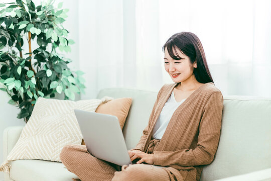 家でノートパソコンを使う日本人女性（ソファ）
