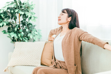 ソファで深呼吸する日本人女性（起床・睡眠・寝起き）
