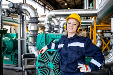 Portrait of smiling female worker standing by diesel generators in production factory.