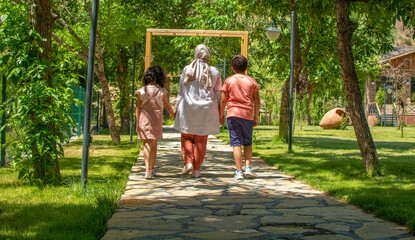 A mother walking in the park with her two children.