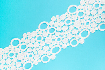 White lace on blue background diagonally with copy space. Close up