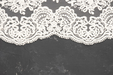 White lace on black concrete background horizontally with copy space. Contrast of tender and rough