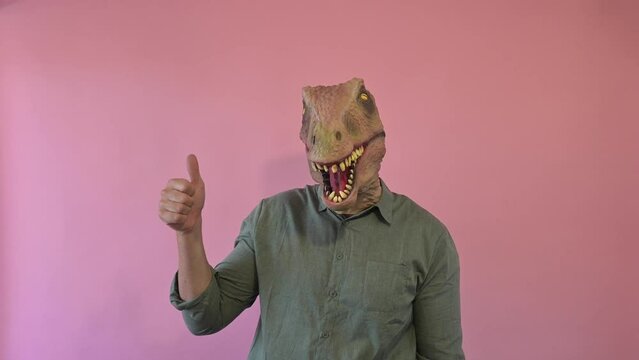 Man with lizard mask on pink background and thumb up.