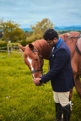 Young brunette rider stroking the head of her brunette horse, vertically