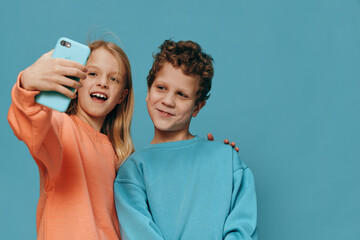 cute, beautiful children, brother and sister stand in bright clothes on a blue background and the...