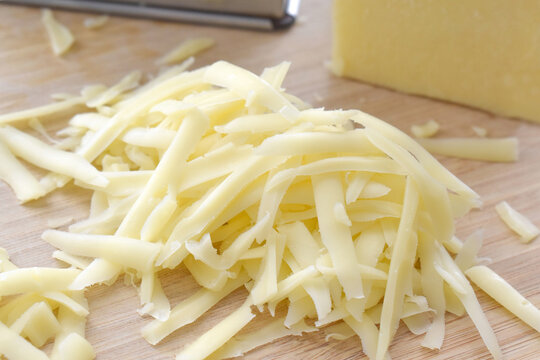 Grated cheese on a bamboo chopping board.