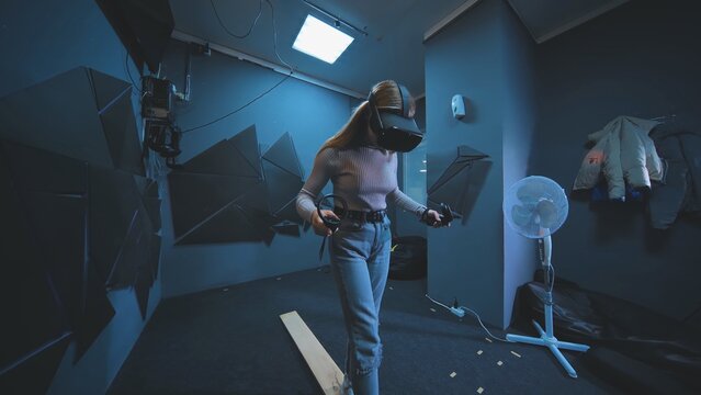 The girl plays a virtual reality game and walks on the board.