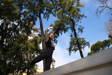 gypsy man with long hair dancing flamenco on an open air stage in a park in seville and he is doing different postures with a lot of passion. Flamenco dance concept cultural heritage of humanity.