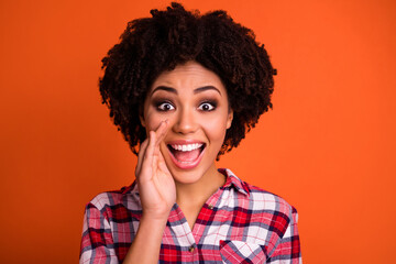 Photo of shiny excited woman wear plaid shirt arm mouth making announcement isolated orange color background