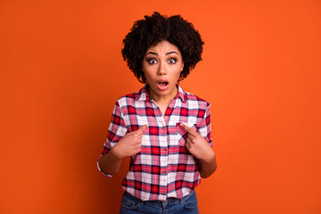 Photo of impressed funny woman wear plaid shirt open mouth pointing fingers herself isolated orange color background