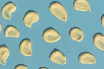 Yellow cream texture on a blue background. Smears of skin care cosmetics product. Wellness and beauty concept. Top view