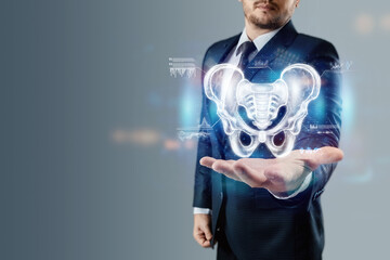 Hologram, x-ray image, anterior view of the male pelvis, sacrum above the arm of a man in a suit. Anatomy, medicine, scientific concepts.