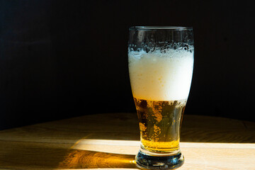 beer in a glass near a green bottle and on a black background