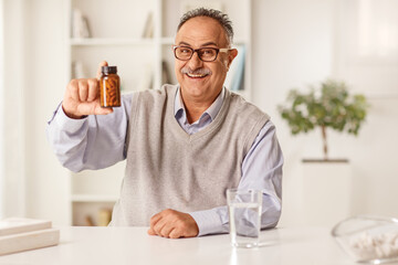 Mature man sitting at home and showing pills