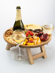 a wooden round bowl with legs, a stand filled with fruits, nuts, wine on a white background. Picnic in nature