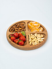 wooden bowl filled with fruits, nuts, strawberries, chocolate on a white background. Picnic in nature