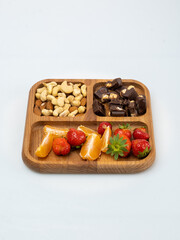 wooden bowl filled with fruits, nuts, strawberries, chocolate on a white background. Picnic in nature