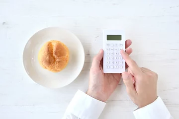 Foto op Plexiglas ダイエットイメージ―シュークリームのカロリーを計算する人物の手元 © takasu
