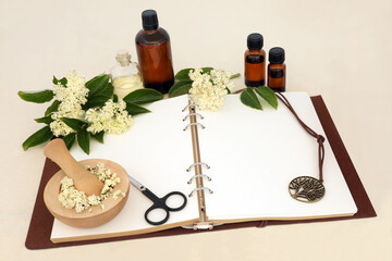Obraz na płótnie Canvas Naturopathic edible elderflower herb flowers used in alternative herbal plant based medicine and aromatherapy with notebook, essential oil bottles. Remedy for cold and flu, bronchitis.