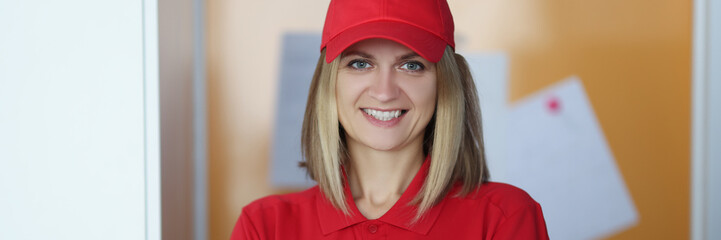 Happy blonde lady courier in red shirt and cap uniform