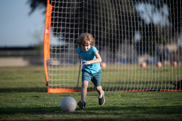 Boy child kicking football on the sports field during soccer match. Boy kicking football on the field.
