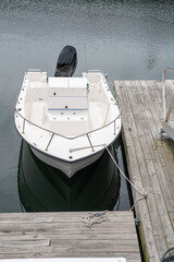 Fototapeta na wymiar Small outboard boat is tied at a dock on a calm day. High quality photo