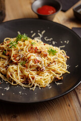 a traditional dish of Italian pasta cuisine. restaurant serving. black plate. wooden table.