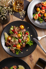 cooking dish, appetizer. Salad. Restaurant serving. black dishes, wooden table.