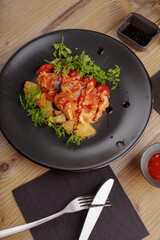 culinary dish chicken steak. restaurant serving. black tableware, wooden table