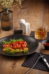 culinary dish chicken steak. restaurant serving. black tableware, wooden table