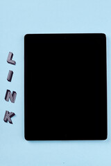 Tablet pc with black screen on blue background. Vertical shot link word and modern device.