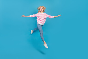 Fototapeta na wymiar Photo of adorable pretty woman wear striped sweater jumping high running arms sides isolated blue color background
