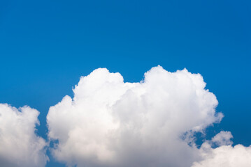 Naklejka na ściany i meble White cloud, gray at base on blue sky background. Half of the image is blue sky