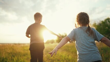 kids run in the park at sunset. happy family children camp kid dream concept. a group of children run on the grass at sunset the rays of the sun fun silhouette. childhood dream teamwork concept