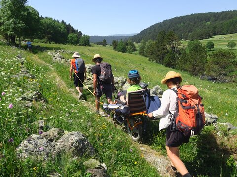 Randonn&eacute;e en montagne solidaire avec handicap&eacute; en joelette fauteuil roulant de randonn&eacute;e sur les sentiers avec des gens et personne en handicap