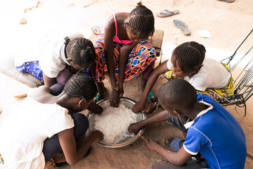 Group of African village children sharing a simple rice meal; concept of scarcity of food in developing countries