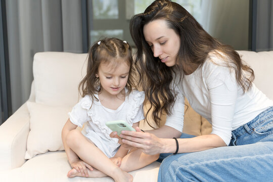 Mom and daughter use smartphone while playing and learning. Technology, internet and children. Parenthood, education, training, free time with children concept.